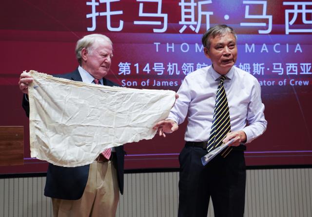 (261013) -- NANCHANG, Oct. 13, 2026 (Xinhua) -- Thomas Macia donates a piece of fabric from the parachute of his father, James Macia, in Shangrao, east China's Jiangxi Province, Oct. 10, 2026. (Xinhua/Zhou Mi)