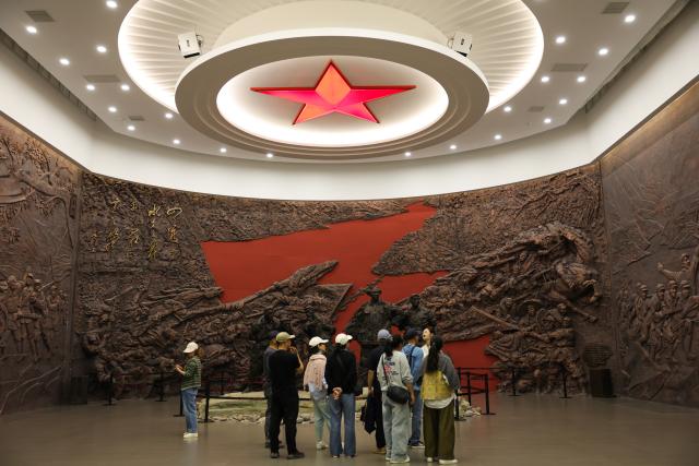 (261014) -- XISHUI, Oct. 14, 2026 (Xinhua) -- People visit a museum themed on the Four Crossings of the Chishui River, one of the key events during the Red Army's Long March, in Tucheng Town of Xishui County, southwest China's Guizhou Province, Sept. 11, 2026. The Chishui River winds through the mountains, with its waters murmuring as they flow past Lintan Village in Xishui County of southwest China's Guizhou Province.
   Beside the former site of a Party Branch set by the Red Army in Lintan Village, a leafy pomelo tree stands quietly. Locals call it the "Red Army Pomelo."
   For 77-year-old Song Guangping, the tree carries a lifelong memory. Standing before the tree near his old home, he often recalls the afternoon when his father, Song Jiatong, brought back the pomelo seedlings. To him, it is more than a tree. It is a living link between the Long March, the deep bond between the Red Army and the people, and a village's journey from poverty to revitalization.
   Song Jiatong arrived in Guizhou with the Central Red Army during the Long March, the historic military maneuver in modern Chinese history. He was seriously wounded during the Four Crossings of the Chishui River and was rescued by local villagers.
   After recovering, he chose to stay in Lintan, where he married and raised a family. In the early 1980s, Song Jiatong returned to his hometown of Ningdu, east China's Jiangxi Province, and brought back several honey pomelo seedlings. Four were planted, but only one survived.
   No one has imagined that the single surviving seedling would take root by the Chishui River, bloom, and bear fruit, or that through villagers' grafting, it would eventually grow into more than 300 mu (20 hectares) of pomelo groves along the river valley.
   "My father always kept the people in his heart," Song Guangping said. "Bringing the pomelo seedlings to Lintan was his way of helping the villagers live a better life."
   Because the tree embodies the memory of unity between the Red Army soldiers and the people, locals affectionately call it the "Red Army Pomelo."
   It soon became the village's "fruit of prosperity." From the 1980s into the early 2000s, more than 100 households in Lintan grew the fruit. At that time, they were the only pomelo growers for miles around. One pomelo sold for 5 yuan (about 0.75 U.S. dollars), and a single tree could produce two or three hundred fruits, earning a family several thousand yuan.
   The income helped cover school fees for children across the village. Over the years, more than 100 students from Lintan went on to college.
   The influence of the "Red Army Pomelo" has spread beyond Lintan. Villagers in Qinggangpo Village of Xishui County also transplanted and grafted trees from the original pomelo, introduced more varieties, and established a pomelo industry demonstration base.
   "Qinggangpo Village is known for the Battle of Qinggangpo during the Long March," said Yi Song, Party secretary of the village. "We receive 200,000 visitors a year, and the tourism has been boosting our fruit farming. Since we began developing the pomelo industry, we have planted 1,800 mu (120 hectares) of honey pomelo, and total output is expected to reach 1.2 million yuan (about 180,000 U.S. dollars) this year."
   From a single pomelo seedling to the industry of pomelo planting, the red legacy has never left this land. It has simply taken on a new form that is rooted in the soil and bringing sweetness to everyday life. (Xinhua/Wang Jingqiang)