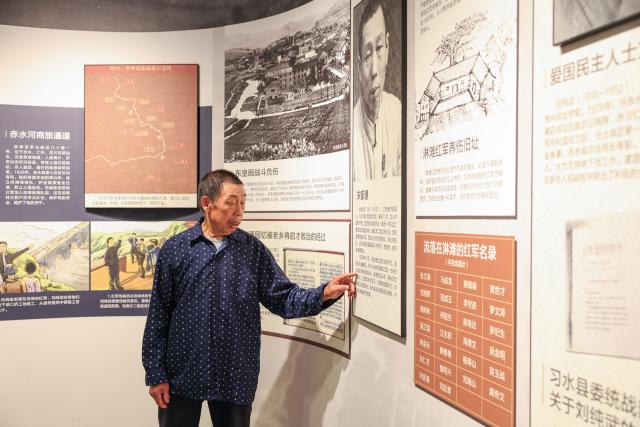 (261014) -- XISHUI, Oct. 14, 2026 (Xinhua) -- Song Guangping, son of late Red Army soldier Song Jiatong, tells the story of his father at a historical exhibition hall in Lintan Village, Xishui County, southwest China's Guizhou Province, Sept. 10, 2026. The Chishui River winds through the mountains, with its waters murmuring as they flow past Lintan Village in Xishui County of southwest China's Guizhou Province.
   Beside the former site of a Party Branch set by the Red Army in Lintan Village, a leafy pomelo tree stands quietly. Locals call it the "Red Army Pomelo."
   For 77-year-old Song Guangping, the tree carries a lifelong memory. Standing before the tree near his old home, he often recalls the afternoon when his father, Song Jiatong, brought back the pomelo seedlings. To him, it is more than a tree. It is a living link between the Long March, the deep bond between the Red Army and the people, and a village's journey from poverty to revitalization.
   Song Jiatong arrived in Guizhou with the Central Red Army during the Long March, the historic military maneuver in modern Chinese history. He was seriously wounded during the Four Crossings of the Chishui River and was rescued by local villagers.
   After recovering, he chose to stay in Lintan, where he married and raised a family. In the early 1980s, Song Jiatong returned to his hometown of Ningdu, east China's Jiangxi Province, and brought back several honey pomelo seedlings. Four were planted, but only one survived.
   No one has imagined that the single surviving seedling would take root by the Chishui River, bloom, and bear fruit, or that through villagers' grafting, it would eventually grow into more than 300 mu (20 hectares) of pomelo groves along the river valley.
   "My father always kept the people in his heart," Song Guangping said. "Bringing the pomelo seedlings to Lintan was his way of helping the villagers live a better life."
   Because the tree embodies the memory of unity between the Red Army soldiers and the people, locals affectionately call it the "Red Army Pomelo."
   It soon became the village's "fruit of prosperity." From the 1980s into the early 2000s, more than 100 households in Lintan grew the fruit. At that time, they were the only pomelo growers for miles around. One pomelo sold for 5 yuan (about 0.75 U.S. dollars), and a single tree could produce two or three hundred fruits, earning a family several thousand yuan.
   The income helped cover school fees for children across the village. Over the years, more than 100 students from Lintan went on to college.
   The influence of the "Red Army Pomelo" has spread beyond Lintan. Villagers in Qinggangpo Village of Xishui County also transplanted and grafted trees from the original pomelo, introduced more varieties, and established a pomelo industry demonstration base.
   "Qinggangpo Village is known for the Battle of Qinggangpo during the Long March," said Yi Song, Party secretary of the village. "We receive 200,000 visitors a year, and the tourism has been boosting our fruit farming. Since we began developing the pomelo industry, we have planted 1,800 mu (120 hectares) of honey pomelo, and total output is expected to reach 1.2 million yuan (about 180,000 U.S. dollars) this year."
   From a single pomelo seedling to the industry of pomelo planting, the red legacy has never left this land. It has simply taken on a new form that is rooted in the soil and bringing sweetness to everyday life. (Xinhua/Wang Jingqiang)