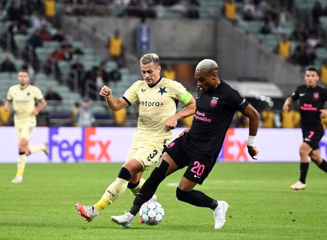 (261014) -- BAKU, Oct. 14, 2026 (Xinhua) -- Tomas Holes (L) of Slavia Praha vies for the ball with Joy-Lance Mickels of Sabah FK during the UEFA Champions League League Stage match in Baku, Azerbaijan, on Oct. 13, 2026. (Photo by Tofik Babayev/Xinhua)