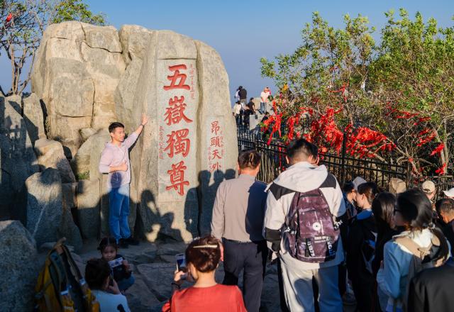 (261014) -- TAI'AN, Oct. 14, 2026 (Xinhua) -- This photo taken on Oct. 7, 2026 shows a visitor posing for photos on Mount Tai in Tai'an City, east China's Shandong Province. Mount Tai, a UNESCO World Heritage Site, is one of China's most renowned mountains, known for its historical, cultural, aesthetic, and scientific significance. (Xinhua/Chen Yehua)