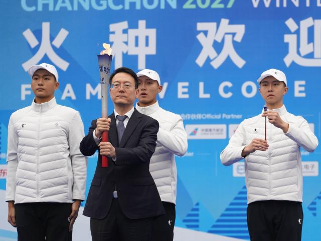 (261014) -- CHANGCHUN, Oct. 14, 2026 (Xinhua) -- Gu Gang, president of the Executive Committee of the Changchun Winter Universiade, presents the torch during a flame welcome ceremony of Changchun 2027 Winter Universiade in Changchun, northeast China's Jilin Province, Oct. 14, 2026. (Xinhua/Yan Linyun)