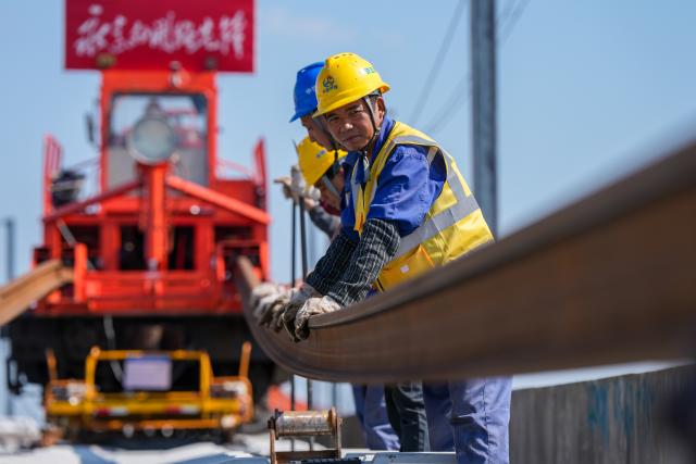 (261014) -- NANJING, Oct. 14, 2026 (Xinhua) -- This photo taken on Oct. 14, 2026 shows constructors laying tracks on the Nantong-Ningbo high-speed railway in east China's Jiangsu Province. A high-speed railway linking Nantong of east China's Jiangsu Province with Ningbo of east China's Zhejiang Province started its track laying on Wednesday. The project is an important part of the coastal channel of China's high-speed rail network, which features eight north-south vertical lines and eight east-west horizontal lines. The new line will promote the high-quality integrated development of the Yangtze River Delta after its completion. (Xinhua/Li Bo)
