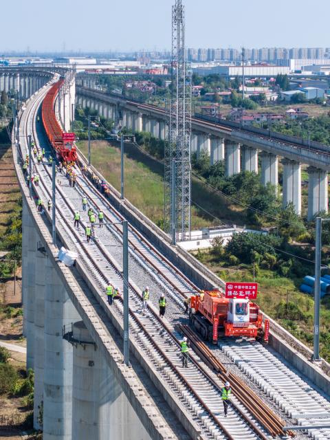 (261014) -- NANJING, Oct. 14, 2026 (Xinhua) -- An aerial drone photo taken on Oct. 14, 2026 shows constructors laying tracks on the Nantong-Ningbo high-speed railway in east China's Jiangsu Province. A high-speed railway linking Nantong of east China's Jiangsu Province with Ningbo of east China's Zhejiang Province started its track laying on Wednesday. The project is an important part of the coastal channel of China's high-speed rail network, which features eight north-south vertical lines and eight east-west horizontal lines. The new line will promote the high-quality integrated development of the Yangtze River Delta after its completion. (Xinhua/Li Bo)