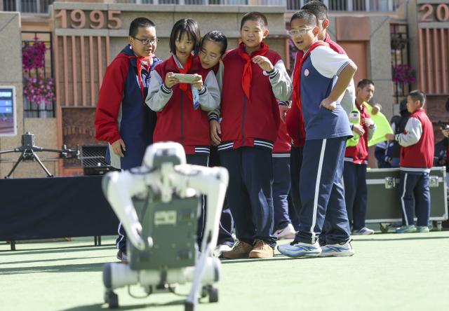 (261014) -- URUMQI, Oct. 14, 2026 (Xinhua) -- A student tries to remotely manipulate a robotic dog during a science and technology festival at a middle school in Urumqi, northwest China's Xinjiang Uygur Autonomous Region, Oct. 14, 2026. (Xinhua/Wang Fei)