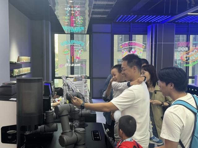 (261015) -- BEIJING, Oct. 15, 2026 (Xinhua) -- Tourists watch a robotic arm making coffee at Robot Mall in Beijing, capital of China, Oct. 2, 2026. TO GO WITH "Feature: Global tourists flock to China to see AI-powered future" (Xinhua/Wang Meiqi)