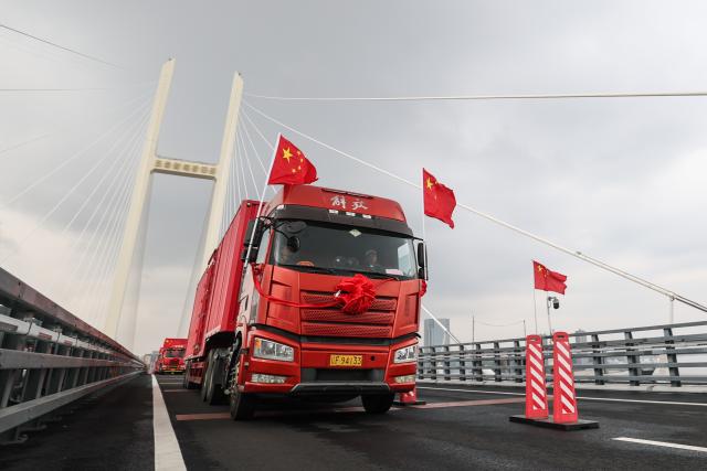 (261015) -- DANDONG, Oct. 15, 2026 (Xinhua) -- This photo taken on Oct. 15, 2026 shows trucks running on the new China-DPRK Yalu River bridge. The new China-DPRK Yalu River bridge officially opened to traffic on Thursday, with both sides jointly holding an opening ceremony on this cross-border artery. (Xinhua/Pan Yulong)