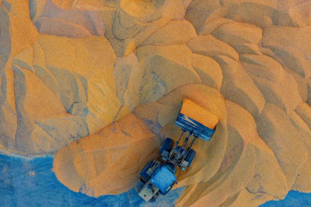 (261015) -- HARBIN, Oct. 15, 2026 (Xinhua) -- An aerial drone photo taken on Oct. 14, 2026 shows a farmer operating a shovel loader to arrange corn piles at a drying yard of a farm under Beidahuang Group in northeast China's Heilongjiang Province. The autumn harvest in Heilongjiang, China's top grain-producing province, has been in full swing. (Xinhua/Zhang Tao)