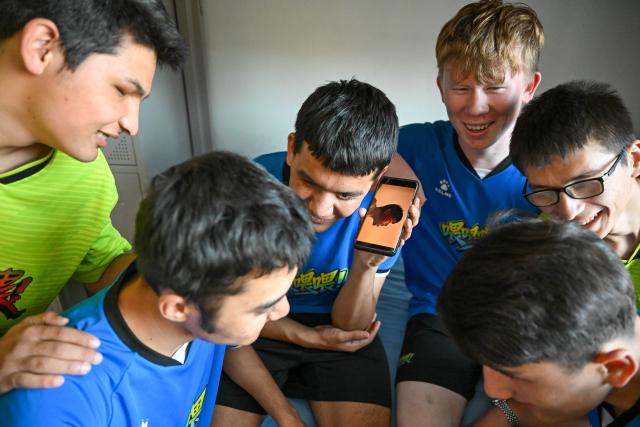 (261015) -- URUMQI, Oct. 15, 2026 (Xinhua) -- Players listen to a documentary after training at Xinjiang Special Education Vocational Secondary School in Changji Hui Autonomous Prefecture, northwest China's Xinjiang Uygur Autonomous Region, Oct. 14, 2026. Xinjiang's first blind football team is known as the 'Wei Wei Wei' team. It takes its name from the call players shout to locate teammates and avoid collisions. This call is the communication code of this special sport.
In blind football, players wear light-blocking blindfolds throughout the match. They track the ball by the bell inside it and keep calling 'wei, wei, wei' to gauge teammates' positions, enabling them to dribble, pass and shoot without sight. In training, they run, collide, feel the boundary boards, and build muscle memory through countless falls and getting back up. For visually impaired teenagers who rarely dare to sprint at full speed in daily life, this enclosed pitch is a place where they can run freely.
'We cannot see the world, but we strive to make the world see us.' In the darkness, guided by their calls and the sound of the ball, these young athletes break through barriers and shine brightly on the green pitch. (Xinhua/Ding Lei)