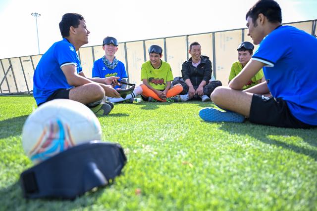 (261015) -- URUMQI, Oct. 15, 2026 (Xinhua) -- Players communicate during the break at Xinjiang Special Education Vocational Secondary School in Changji Hui Autonomous Prefecture, northwest China's Xinjiang Uygur Autonomous Region, Oct. 14, 2026. Xinjiang's first blind football team is known as the 'Wei Wei Wei' team. It takes its name from the call players shout to locate teammates and avoid collisions. This call is the communication code of this special sport.
In blind football, players wear light-blocking blindfolds throughout the match. They track the ball by the bell inside it and keep calling 'wei, wei, wei' to gauge teammates' positions, enabling them to dribble, pass and shoot without sight. In training, they run, collide, feel the boundary boards, and build muscle memory through countless falls and getting back up. For visually impaired teenagers who rarely dare to sprint at full speed in daily life, this enclosed pitch is a place where they can run freely.
'We cannot see the world, but we strive to make the world see us.' In the darkness, guided by their calls and the sound of the ball, these young athletes break through barriers and shine brightly on the green pitch. (Xinhua/Ding Lei)