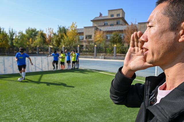 (261015) -- URUMQI, Oct. 15, 2026 (Xinhua) -- The coach calls out "wei wei wei" during the training at Xinjiang Special Education Vocational Secondary School in Changji Hui Autonomous Prefecture, northwest China's Xinjiang Uygur Autonomous Region, Oct. 14, 2026. Xinjiang's first blind football team is known as the 'Wei Wei Wei' team. It takes its name from the call players shout to locate teammates and avoid collisions. This call is the communication code of this special sport.
In blind football, players wear light-blocking blindfolds throughout the match. They track the ball by the bell inside it and keep calling 'wei, wei, wei' to gauge teammates' positions, enabling them to dribble, pass and shoot without sight. In training, they run, collide, feel the boundary boards, and build muscle memory through countless falls and getting back up. For visually impaired teenagers who rarely dare to sprint at full speed in daily life, this enclosed pitch is a place where they can run freely.
'We cannot see the world, but we strive to make the world see us.' In the darkness, guided by their calls and the sound of the ball, these young athletes break through barriers and shine brightly on the green pitch. (Xinhua/Ding Lei)