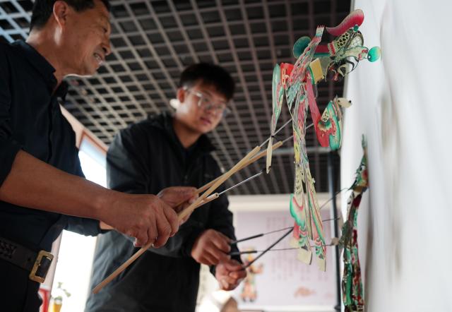 (261015) -- SHENYANG, Oct. 15, 2026 (Xinhua) -- Xu Zilin (L) instructs one of his apprentices on shadow puppetry maneuver in Lingyuan City, northeast China's Liaoning Province, Oct. 10, 2026.
  Lingyuan shadow puppetry, a national-level intangible cultural heritage in China, comes vividly alive amid dazzling light and shadow. Movements of the puppets embody the local folk traditions, which have been passed down through generations.
  Xu Zilin was born in 1964 to a family that has the Lingyuan shadow puppetry as its walk of life for ages. More than 40 years of professional experience made Xu a representative inheritor of the craft and an influential figure in the trade. Many of his vocal passages have been modeled for teaching.
  To better promote shadow plays, Xu founded a shadow puppetry troupe and brought quality productions to the grassroots level. Over the years, Xu and his troupe have performed more than 4,000 shows in Liaoning and neighboring provinces. (Xinhua/Li Gang)