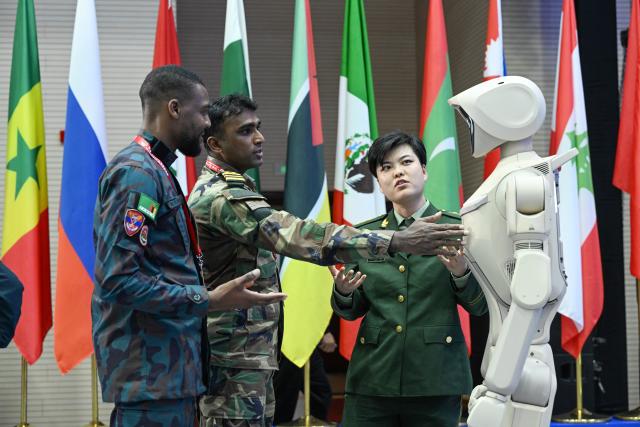 (261015) -- BEIJING, Oct. 15, 2026 (Xinhua) -- Participants interact with a robot during the Great Wall-2026 International Forum on Counter-Terrorism in Beijing, capital of China, Oct. 14, 2026. The Great Wall-2026 International Forum on Counter-Terrorism concluded here on Thursday. (Photo by Ze Fangningchen/Xinhua)