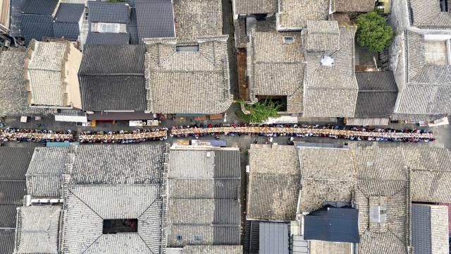(261015) -- LANXI, Oct. 15, 2026 (Xinhua) -- An aerial drone photo taken on Oct. 15, 2026 shows a view of a long-table banquet held for the elderly in Yanggang Village of Lanxi, east China's Zhejiang Province. Funded by kind-hearted people, the banquet held on Thursday was attended by more than 500 people aged 60 and above to mark the upcoming Double Ninth Festival. Celebrated on the ninth day of the ninth lunar month, it is an occasion to care for and send blessings to older people in China. (Photo by Hu Xiaofei/Xinhua)
