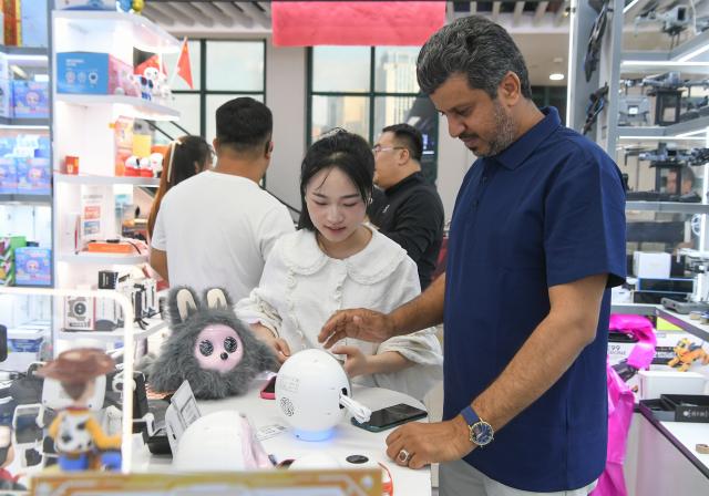 (261016) -- BEIJING, Oct. 16, 2026 (Xinhua) -- A merchant selects intelligent toys at the Yiwu International Trade Market in Yiwu, east China's Zhejiang Province, Oct. 9, 2026. (Photo by Shi Kuanbing/Xinhua)
