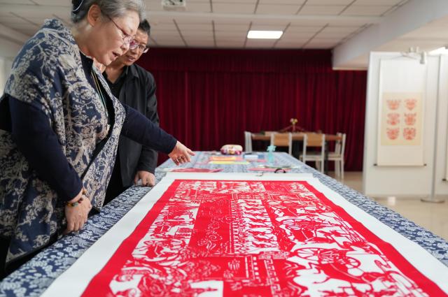 (261016) -- CHAOYANG, Oct. 16, 2026 (Xinhua) -- Yang Zhihong (front) introduces papercut works at an art exhibition hall in Jianping County of Chaoyang City, northeast China's Liaoning Province, Oct. 10, 2026. Known for its bold, rustic style and designs inspired by folk stories and traditional symbols, Jianping paper-cutting reflects the rich culture of western Liaoning Province.
   Born in 1972, Yang Zhihong is a representative inheritor of Jianping paper-cutting, a provincial-level intangible cultural heritage of Liaoning Province. Inspired by local folk artists from an early age, she has devoted herself to preserving this traditional art. 
   Over decades of practice, Yang has won several major industry awards. Today, she continues to explore the art's cultural heritage and create new works, keeping this ancient folk tradition alive. (Xinhua/Li Gang)