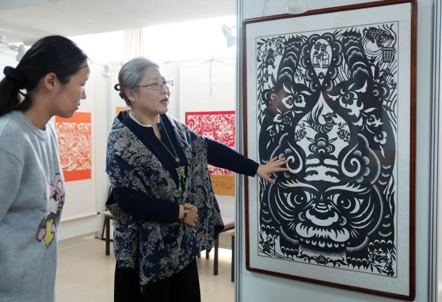 (261016) -- CHAOYANG, Oct. 16, 2026 (Xinhua) -- Yang Zhihong (R) introduces papercut works at an art exhibition hall in Jianping County of Chaoyang City, northeast China's Liaoning Province, Oct. 10, 2026. Known for its bold, rustic style and designs inspired by folk stories and traditional symbols, Jianping paper-cutting reflects the rich culture of western Liaoning Province.
   Born in 1972, Yang Zhihong is a representative inheritor of Jianping paper-cutting, a provincial-level intangible cultural heritage of Liaoning Province. Inspired by local folk artists from an early age, she has devoted herself to preserving this traditional art. 
   Over decades of practice, Yang has won several major industry awards. Today, she continues to explore the art's cultural heritage and create new works, keeping this ancient folk tradition alive. (Xinhua/Li Gang)