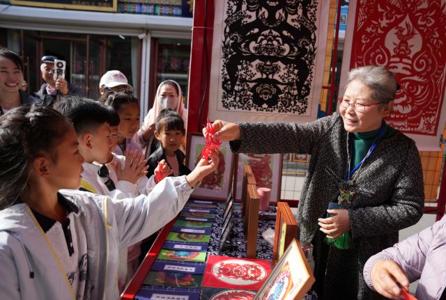 (261016) -- CHAOYANG, Oct. 16, 2026 (Xinhua) -- Yang Zhihong (R) shows her papercut works at a market in Jianping County of Chaoyang City, northeast China's Liaoning Province, Oct. 16, 2026. Known for its bold, rustic style and designs inspired by folk stories and traditional symbols, Jianping paper-cutting reflects the rich culture of western Liaoning Province.
   Born in 1972, Yang Zhihong is a representative inheritor of Jianping paper-cutting, a provincial-level intangible cultural heritage of Liaoning Province. Inspired by local folk artists from an early age, she has devoted herself to preserving this traditional art. 
   Over decades of practice, Yang has won several major industry awards. Today, she continues to explore the art's cultural heritage and create new works, keeping this ancient folk tradition alive. (Xinhua/Li Gang)