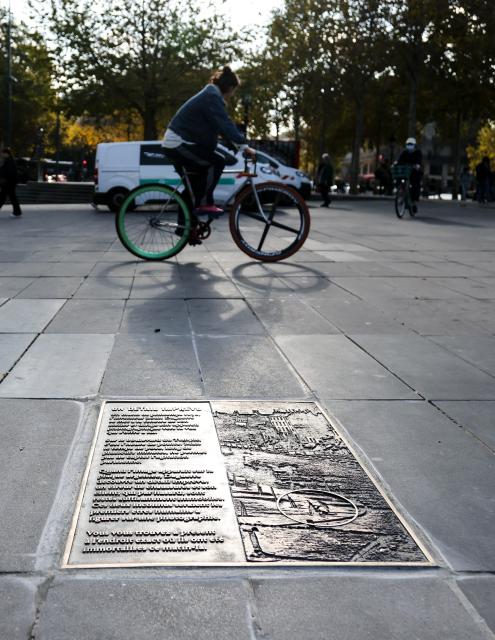 (261016) -- PARIS, Oct. 16, 2026 (Xinhua) -- People ride past a plaque titled "An Unexpected Detail" in Paris, France, Oct. 16, 2026. A bronze plaque titled "An Unexpected Detail" was unveiled at Place de la Republique in Paris on Thursday. It honors "Boulevard du Temple," an image taken in 1838 by French photography pioneer Louis Daguerre and believed to be the first photograph to show people. (Xinhua/Wu Huiwo)