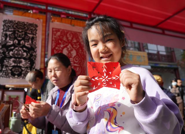(261017) -- CHAOYANG, Oct. 17, 2026 (Xinhua) -- A girl displays her paper-cutting work at an intangible cultural heritage fair, a supporting event of the 4th annual conference on intangible cultural heritage safeguarding in China, in Chaoyang, northeast China's Liaoning Province, Oct. 16, 2026. The three-day annual conference hosts multiple cultural activities, allowing the public to feel the charm of intangible cultural heritage up close. (Xinhua/Li Gang)