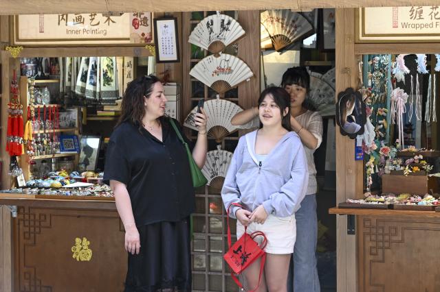 (261017) -- SHANGHAI, Oct. 17, 2026 (Xinhua) -- A foreign tourist tries on hair ornaments at a mall in Shanghai, east China, May 5, 2026. (Xinhua/Chen Haoming)