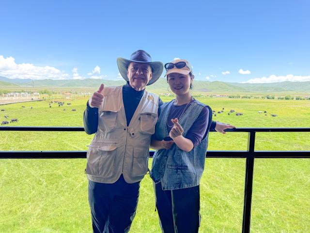 (261017) -- CHENGDU, Oct. 17, 2026 (Xinhua) -- Luo Lan (R) poses for a photo with a foreign tourist at her homestay in Xiahalama Village of Hongyuan County of Aba Tibetan and Qiang Autonomous Prefecture, southwest China's Sichuan Province, July 9, 2026. TO GO WITH "Across China: A young returnee's bet on the 'sea of death'" (Xinhua/Wang Xi)