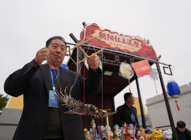 (261017) -- SHENYANG, Oct. 17, 2026 (Xinhua) -- Sun Yu'en displays his Chaoyang red clay figure work at a market for intangible cultural heritage in Chaoyang, northeast China's Liaoning Province, Oct. 16, 2026. Chaoyang red clay figure is a provincial-level intangible cultural heritage in Liaoning Province, northeast China. 
  Sun Yu'en, an inheritor of this craft, has loved the art since childhood. In 1998, he devoted himself to the craft and learned the core skills from his teacher. Sun's artworks emphasize the expressions and details of the figures, embodying rustic charm. He has also created a series of moving clay figures, which are popular among young people. (Xinhua/Li Gang)