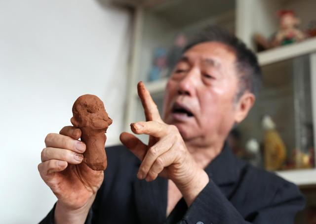 (261017) -- SHENYANG, Oct. 17, 2026 (Xinhua) -- Sun Yu'en introduces the details of a Chaoyang red clay figure work at his studio in Chaoyang, northeast China's Liaoning Province, Oct. 10, 2026. Chaoyang red clay figure is a provincial-level intangible cultural heritage in Liaoning Province, northeast China. 
  Sun Yu'en, an inheritor of this craft, has loved the art since childhood. In 1998, he devoted himself to the craft and learned the core skills from his teacher. Sun's artworks emphasize the expressions and details of the figures, embodying rustic charm. He has also created a series of moving clay figures, which are popular among young people. (Xinhua/Li Gang)