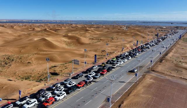 (261017) -- ZHONGWEI, Oct. 17, 2026 (Xinhua) -- An aerial drone photo taken on Oct. 17, 2026 shows vehicles gathering at the Shapotou scenic area in Zhongwei, northwest China's Ningxia Hui Autonomous Region. Marking the beginning of a desert self-driving event, a ceremony was held here on Saturday, gathering more than 500 vehicles for self-driving tours and over 1,000 tourists. (Xinhua/Wang Peng)
