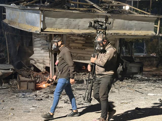 (261017) -- TIRANA, Oct. 17, 2026 (Xinhua) -- Journalists walk past a kiosk damaged during protests in Tirana, Albania, Oct. 15, 2026. Protests in Albania continued on Saturday, which have escalated into violent clashes with police and left government buildings, banks, businesses and public facilities damaged in the capital Tirana. (Photo by Jin Qiao/Xinhua)
