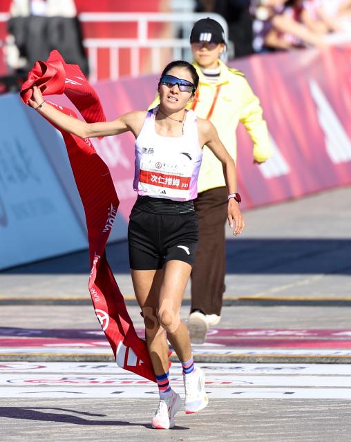 (261018) -- BEIJING, Oct. 18, 2026 (Xinhua) -- Cirencuomu of China crosses the finish line to win the second place of the women's marathon event at the 2026 Beijing Marathon & National Marathon Championships in Beijing, capital of China, Oct. 18, 2026. (Xinhua/Luo Yuan)