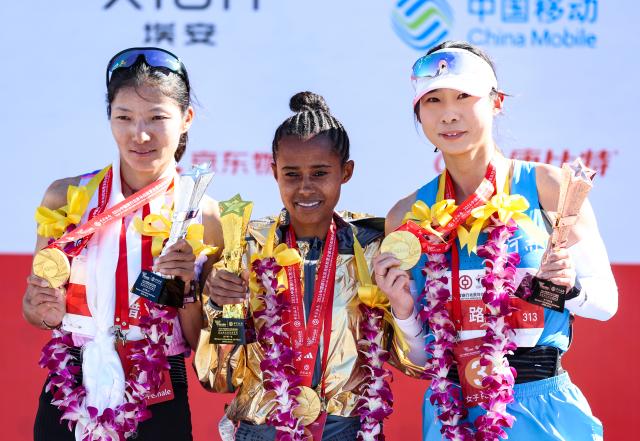 (261018) -- BEIJING, Oct. 18, 2026 (Xinhua) -- (L to R)Second-placed Cirencuomu of China, first-placed Anchinalu Dessie Genaneh of Ethiopia and third-placed Lu Ying of China pose during the awarding ceremony for the women's marathon event at the 2026 Beijing Marathon & National Marathon Championships in Beijing, capital of China, Oct. 18, 2026. (Xinhua/Luo Yuan)