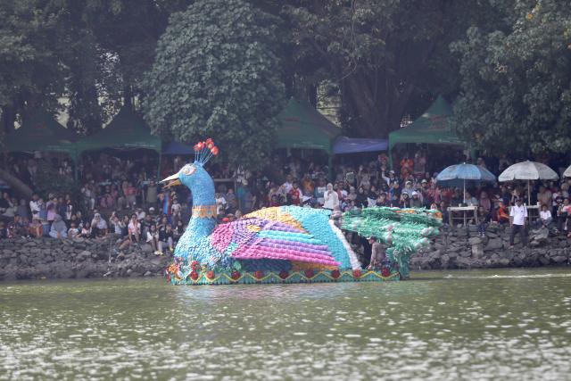 (261018) -- JAKARTA, Oct. 18, 2026 (Xinhua) -- People watch participants taking a boat decorated with recycled plastic bottles during the Festival Cinta Lingkungan 2026 (CiLung Fest), or Eco-Friendly Boat Festival, in Jakarta, Indonesia, Oct. 18, 2026. (Photo by B. Nugraha/Xinhua)