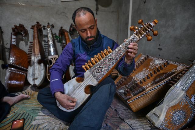 (261018) -- SRINAGAR, Oct. 18, 2026 (Xinhua) -- A musician examines a rabab before purchasing it at the workshop of Mushtaq Ahmad Dar in the outskirts of Srinagar city, the summer capital of Indian-controlled Kashmir, Oct. 12, 2026. TO GO WITH "Feature: Indian-controlled Kashmir's traditional musical instrument makers strive to keep vanishing craft alive" (Xinhua/Javed Dar)