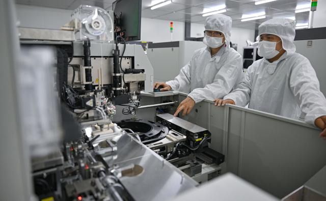 (261018) -- HAIKOU, Oct. 18, 2026 (Xinhua) -- Staff members check the pick-and-plate machine at a workshop in Hainan Hangxin High-Tech Industrial Park in Haikou, south China's Hainan Province, Oct. 18, 2026.
  Leveraging policy benefits and incentives, the Hainan Free Trade Port, under the island-wide special customs operations, is committed to building itself into a hub for Chinese semiconductors and chips to go global. (Xinhua/Guo Cheng)