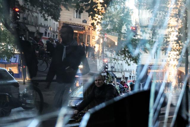 (261018) -- PARIS, Oct. 18, 2026 (Xinhua) -- People walk past a shop damaged during a protest in Paris, France, Oct. 18, 2026. French President Emmanuel Macron on Sunday vowed legal action against those responsible for violence during protests across the country on Saturday. (Xinhua/Wu Huiwo)