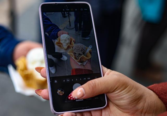 (261018) -- MEXICO CITY, Oct. 18, 2026 (Xinhua) -- A woman takes a photo of Catrina-shaped ice creams with her mobile phone in Mexico City, capital of Mexico, Oct. 17, 2026. As the Day of the Dead approaches, an ice cream shop in Mexico City has introduced Catrina-shaped ice creams, attracting many local residents and tourists. (Photo by Francisco Canedo/Xinhua)