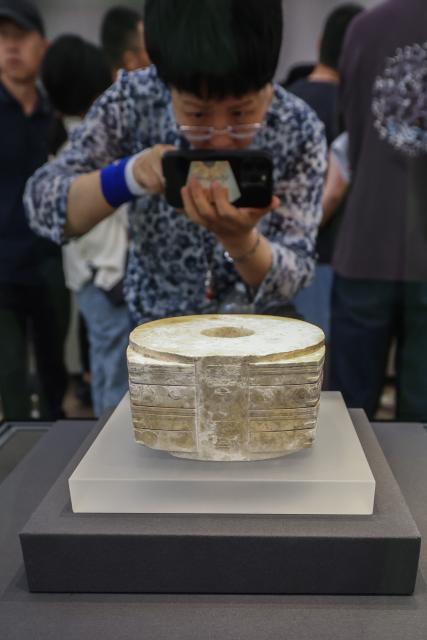 (261019) -- HANGZHOU, Oct. 19, 2026 (Xinhua) -- A visitor takes photos of one of the largest jade congs (a ritual object featuring a square outer form and a circular inner tube) at a special exhibition marking the 90th anniversary of the discovery of the Liangzhu archaeological site in Hangzhou, east China's Zhejiang Province, Oct. 18, 2026. The year 2026 marks the 90th anniversary of the discovery of the Liangzhu ruins. The fourth Liangzhu Forum, which opened Sunday in Hangzhou, has rolled out a series of concurrent cultural events including a sub-forum, a themed special exhibition and a tour in the Archaeological Ruins of Liangzhu City Park. (Xinhua/Xu Yu)