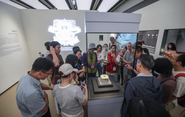 (261019) -- HANGZHOU, Oct. 19, 2026 (Xinhua) -- Visitors view one of the largest jade congs (a ritual object featuring a square outer form and a circular inner tube) at a special exhibition marking the 90th anniversary of the discovery of the Liangzhu archaeological site in Hangzhou, east China's Zhejiang Province, Oct. 18, 2026. The year 2026 marks the 90th anniversary of the discovery of the Liangzhu ruins. The fourth Liangzhu Forum, which opened Sunday in Hangzhou, has rolled out a series of concurrent cultural events including a sub-forum, a themed special exhibition and a tour in the Archaeological Ruins of Liangzhu City Park. (Xinhua/Xu Yu)