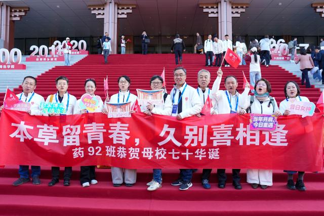 (261019) -- BEIJING, Oct. 19, 2026 (Xinhua) -- Alumni pose for photos in front of the library at the Liangxiang campus of Beijing University of Chinese Medicine in Beijing, capital of China, Oct. 19, 2026. A series of events are held on Monday to commemorate the 70th anniversary of the founding of Beijing University of Chinese Medicine. (Xinhua/Ju Huanzong)