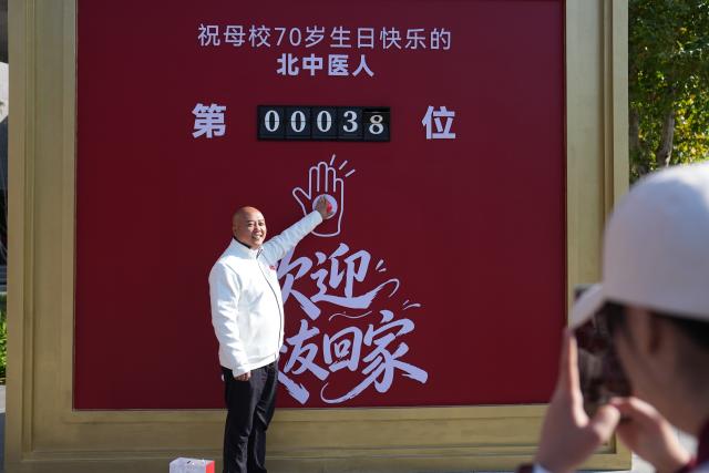 (261019) -- BEIJING, Oct. 19, 2026 (Xinhua) -- An alumnus poses for photos at the Liangxiang campus of Beijing University of Chinese Medicine in Beijing, capital of China, Oct. 19, 2026. A series of events are held on Monday to commemorate the 70th anniversary of the founding of Beijing University of Chinese Medicine. (Xinhua/Ju Huanzong)