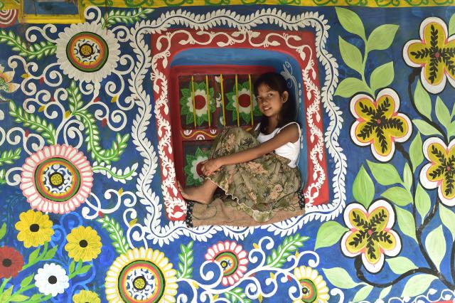 (261019) -- CHAPAINAWABGANJ, Oct. 19, 2026 (Xinhua) -- A child is seen at a house decorated with "Alpona" in a village in Chapainawabganj District, Bangladesh, Oct. 18, 2026. "Alpona" is a traditional form of folk art practiced in South Asia and is mainly created by women in the local community. (Photo by Habibur Rahman/Xinhua)