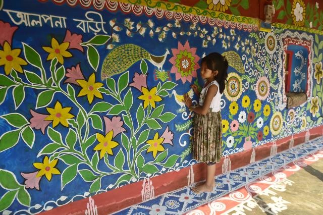 (261019) -- CHAPAINAWABGANJ, Oct. 19, 2026 (Xinhua) -- A child is seen at a house decorated with "Alpona" in a village in Chapainawabganj District, Bangladesh, Oct. 18, 2026. "Alpona" is a traditional form of folk art practiced in South Asia and is mainly created by women in the local community. (Photo by Habibur Rahman/Xinhua)
