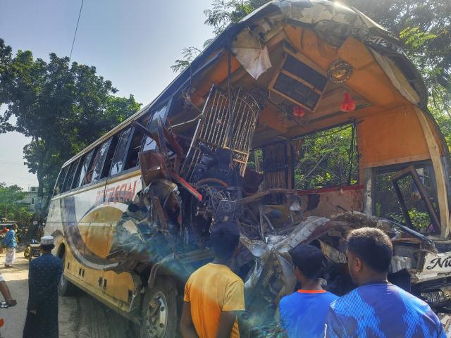 (261020) -- DHAKA, Oct. 20, 2026 (Xinhua) -- This photo taken by a mobile phone shows people looking at a crashed passenger bus in Natore district, Bangladesh, Oct. 20, 2026. A head-on collision between a passenger bus and a sand-laden truck in Bangladesh's Natore district, some 200 km northwest of the capital Dhaka, early Tuesday left at least 14 people dead and 20 others injured, a senior police official said. (Xinhua)