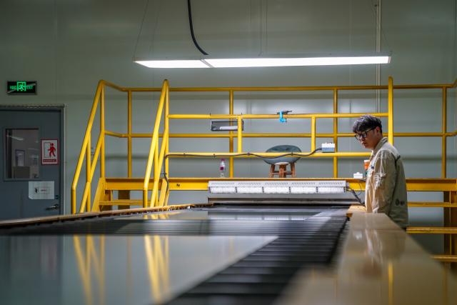 (261020) -- ZHAOTONG, Oct. 20, 2026 (Xinhua) -- A staff member works in the workshop of Zhaotong Kibing Photovoltaic Technology Co,. Ltd. in Zhaotong City, southwest China's Yunnan Province, on Oct. 19, 2026. Leveraging its advantages in rich resources of silicon ore and the development of green electricity, Zhaotong City has attracted leading enterprises to develop the photovoltaic glass manufacturing industry, bringing about employment for surrounding residents. Currently, the city has basically formed an industrial chain from silicon mining and washing to the manufacturing of photovoltaic glass and photovoltaic modules. (Xinhua/Peng Yikai)