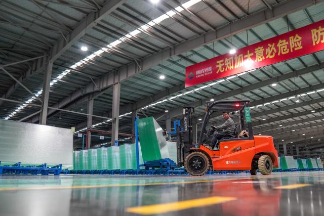 (261020) -- ZHAOTONG, Oct. 20, 2026 (Xinhua) -- A staff member transports photovoltaic glass products in the workshop of Zhaotong Kibing Photovoltaic Technology Co,. Ltd. in Zhaotong City, southwest China's Yunnan Province, on Oct. 19, 2026. Leveraging its advantages in rich resources of silicon ore and the development of green electricity, Zhaotong City has attracted leading enterprises to develop the photovoltaic glass manufacturing industry, bringing about employment for surrounding residents. Currently, the city has basically formed an industrial chain from silicon mining and washing to the manufacturing of photovoltaic glass and photovoltaic modules. (Xinhua/Peng Yikai)