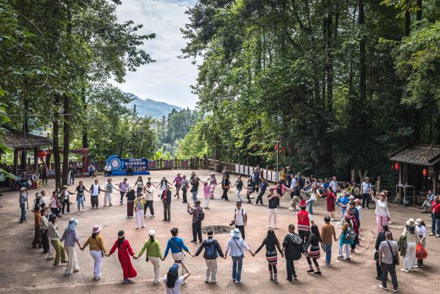 (261020) -- TENGCHONG, Oct. 20, 2026 (Xinhua) -- Tourists participate in a dance with artists in Simola Wa Village in Qingshui Town of Tengchong City, southwest China's Yunnan Province, Oct. 19, 2026. The Simola Wa Village has a history of over 500 years and is home to people of multiple ethnic groups including the Wa, Han, Bai and Dai. Simola means "a place of happiness" in the Wa language. In recent years, the village has relied on its ethnic cultural resources to create a distinctive cultural tourism industry, attracting a continuous stream of tourists. (Xinhua/Wang Guansen)