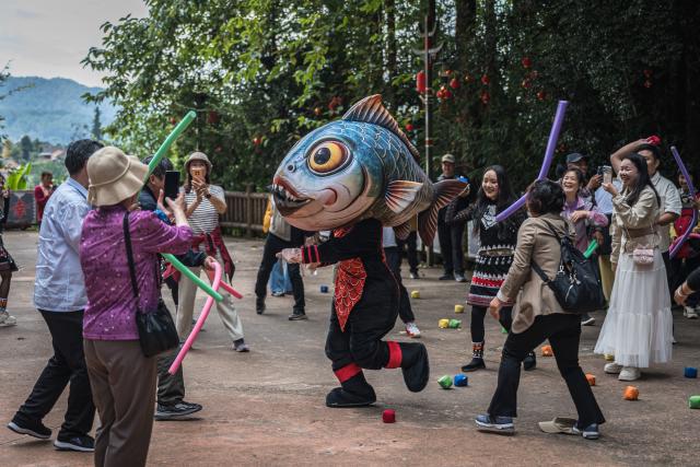 (261020) -- TENGCHONG, Oct. 20, 2026 (Xinhua) -- Tourists participate in a folk activity in Simola Wa Village in Qingshui Town of Tengchong City, southwest China's Yunnan Province, Oct. 19, 2026. The Simola Wa Village has a history of over 500 years and is home to people of multiple ethnic groups including the Wa, Han, Bai and Dai. Simola means "a place of happiness" in the Wa language. In recent years, the village has relied on its ethnic cultural resources to create a distinctive cultural tourism industry, attracting a continuous stream of tourists. (Xinhua/Wang Guansen)