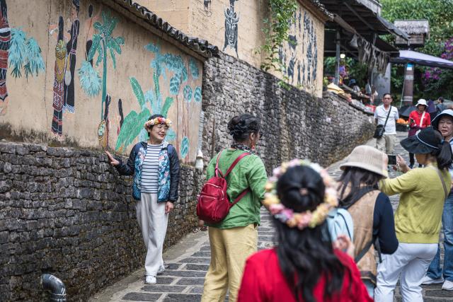 (261020) -- TENGCHONG, Oct. 20, 2026 (Xinhua) -- A tourist poses for photos in Simola Wa Village in Qingshui Town of Tengchong City, southwest China's Yunnan Province, Oct. 19, 2026. The Simola Wa Village has a history of over 500 years and is home to people of multiple ethnic groups including the Wa, Han, Bai and Dai. Simola means "a place of happiness" in the Wa language. In recent years, the village has relied on its ethnic cultural resources to create a distinctive cultural tourism industry, attracting a continuous stream of tourists. (Xinhua/Wang Guansen)