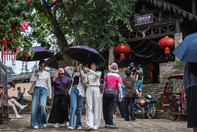 (261020) -- TENGCHONG, Oct. 20, 2026 (Xinhua) -- Tourists visit Simola Wa Village in Qingshui Town of Tengchong City, southwest China's Yunnan Province, Oct. 19, 2026. The Simola Wa Village has a history of over 500 years and is home to people of multiple ethnic groups including the Wa, Han, Bai and Dai. Simola means "a place of happiness" in the Wa language. In recent years, the village has relied on its ethnic cultural resources to create a distinctive cultural tourism industry, attracting a continuous stream of tourists. (Xinhua/Wang Guansen)